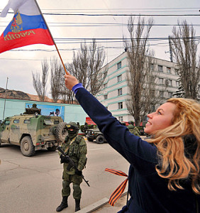 Pro-Russian woman waves a Russian flag in support of armed men in military fatigues in Balaklava